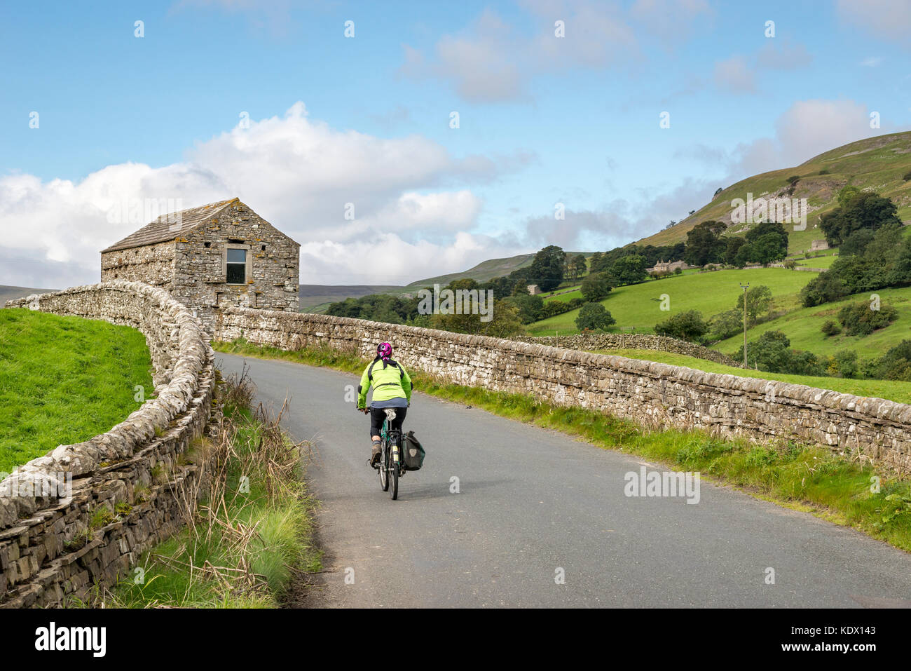 Cyclist on a country road near Muker in Swaledale, Yorkshire Dales national park, England. Stock Photo
