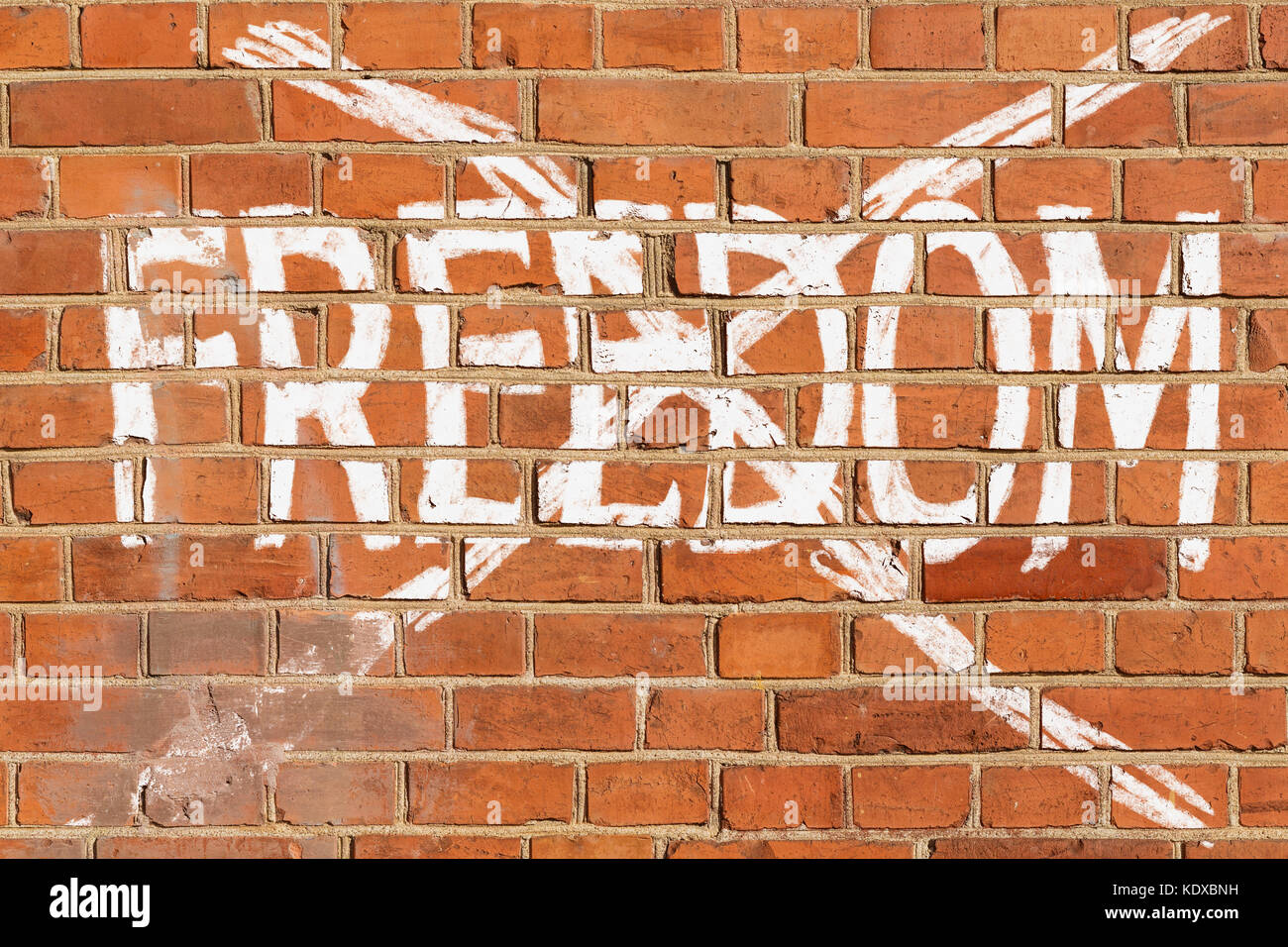 Brick wall with the crossed out word FREEDOM Stock Photo