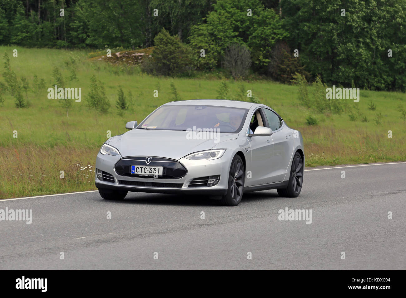 PAIMIO, FINLAND - JUNE 23, 2016: Grey Tesla Model S electric car moves along asphalt road in South of Finland at summer. Stock Photo