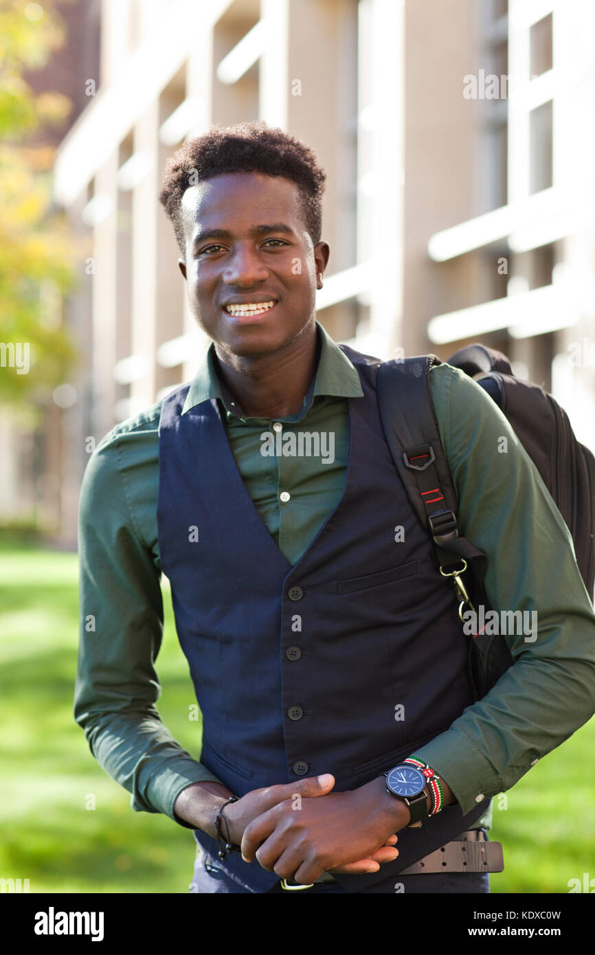 Handsome young black student man with backpack smiles on college campus Stock Photo