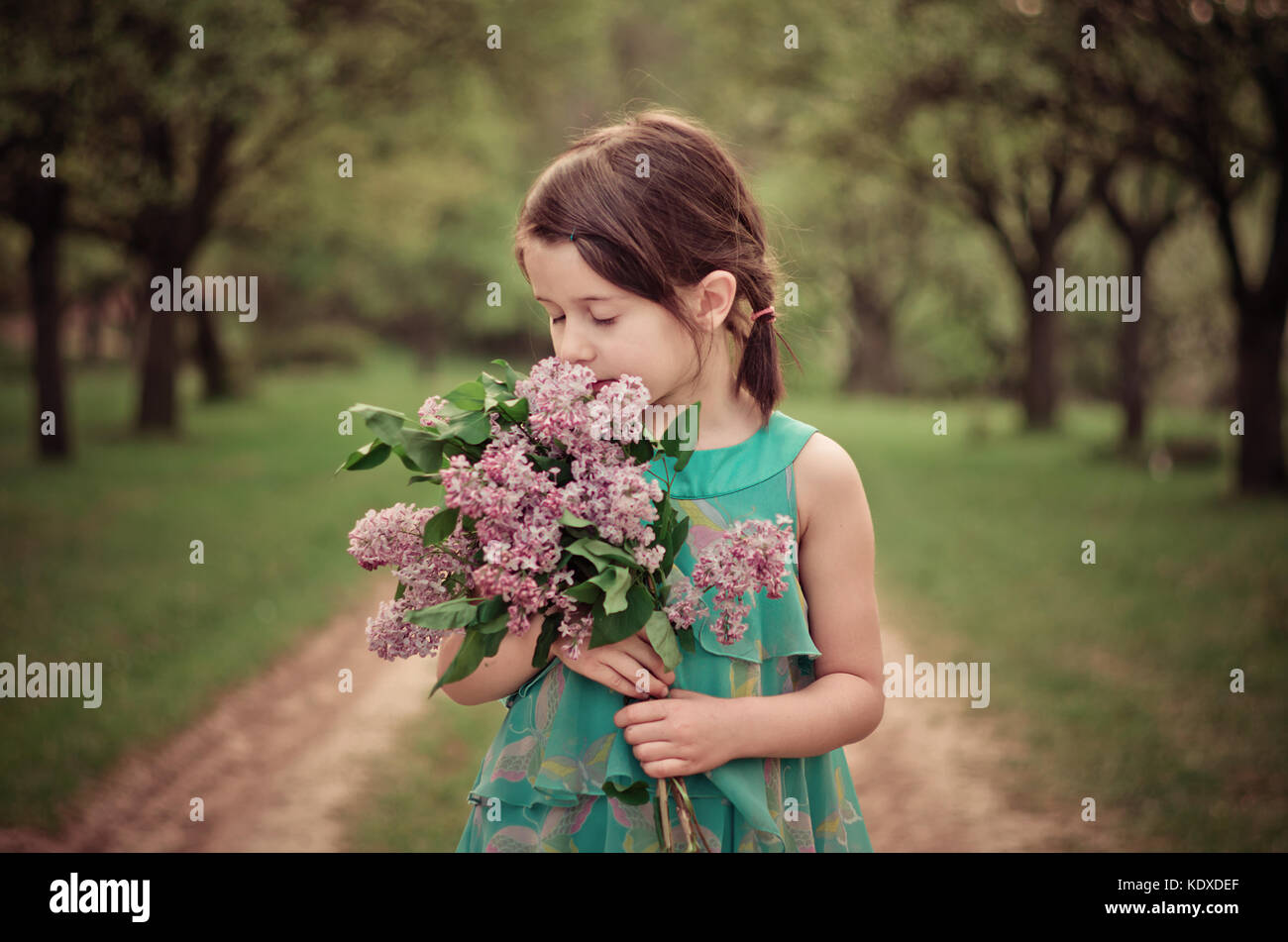 Pretty girl holding bouquet of flowers and smelling. Eyes closed ...