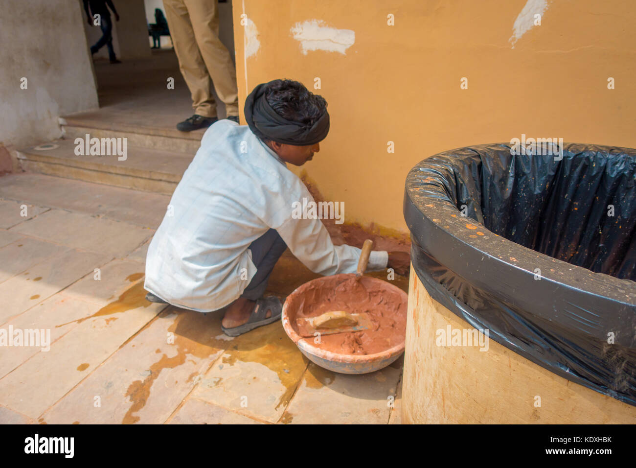 Amber, India - September 19, 2017: Unidentified Indian man wearing a white t-shirt and grey pants, working with clay fixing wall problems in the city of Amber, India Stock Photo