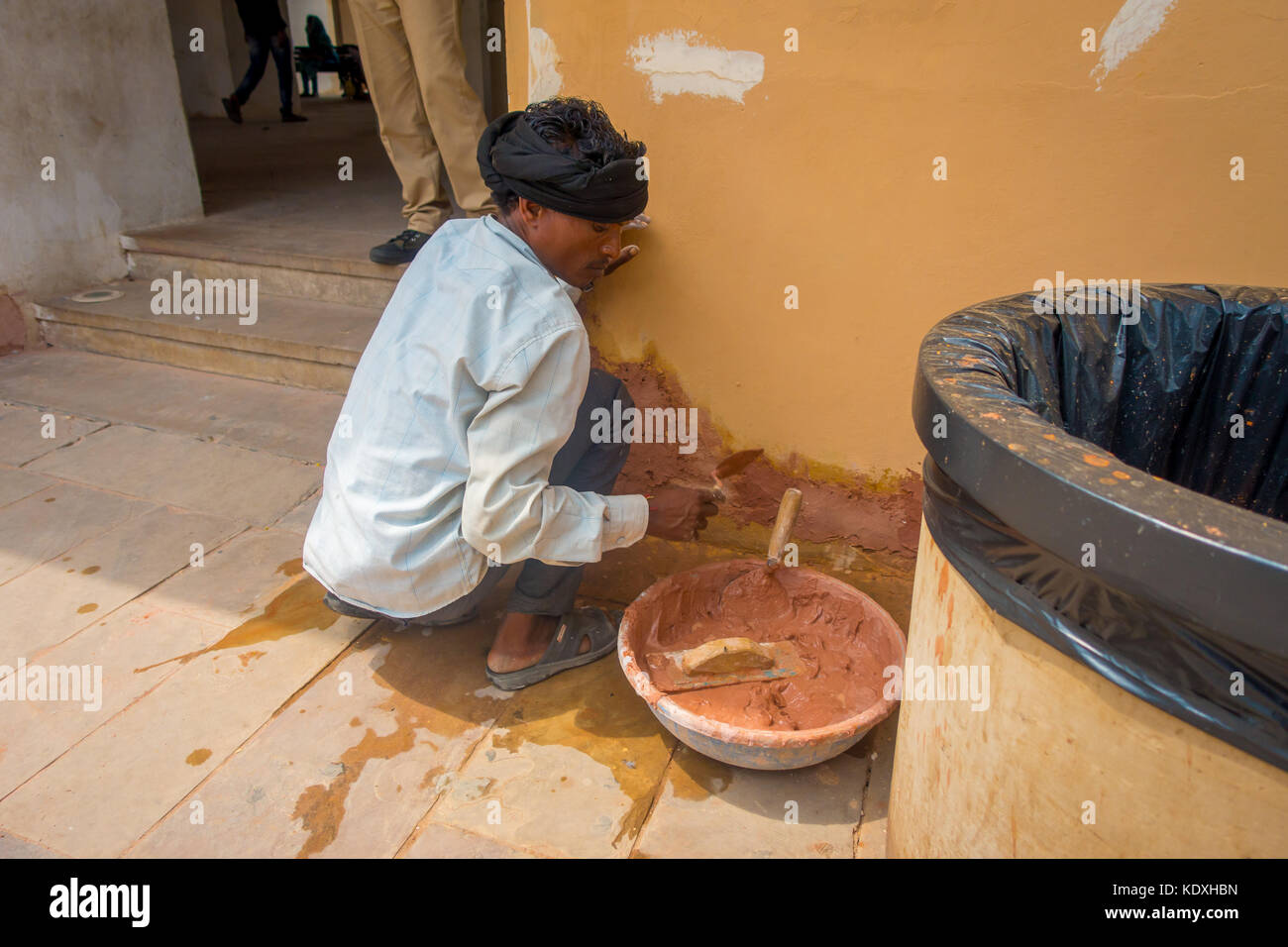 Amber, India - September 19, 2017: Unidentified Indian man wearing a white t-shirt and grey pants, working with clay fixing wall problems in the city of Amber, India Stock Photo