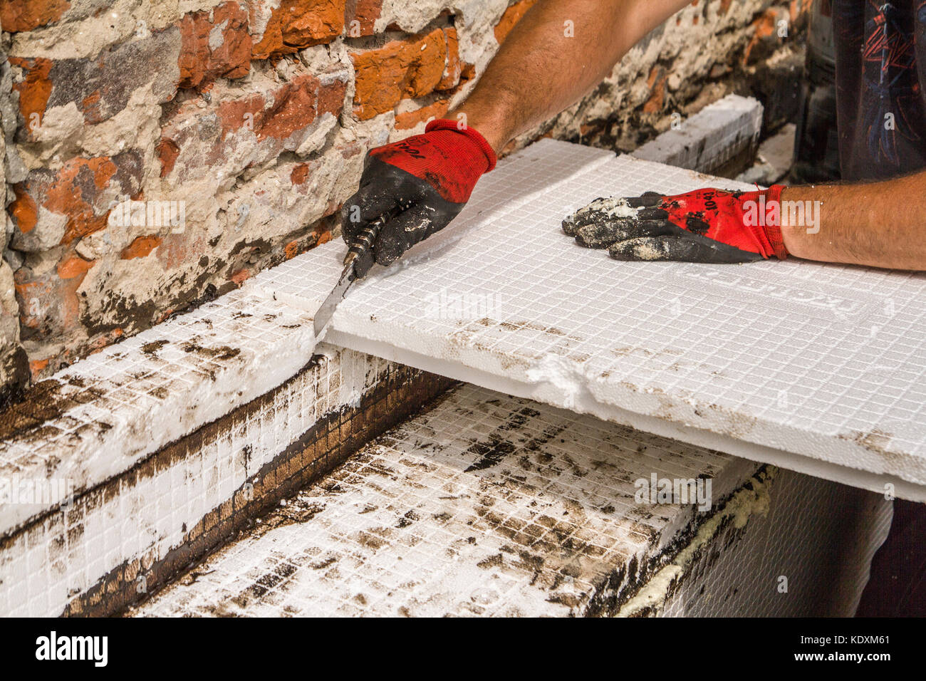 Construction worker thermally insulating house foundation walls with