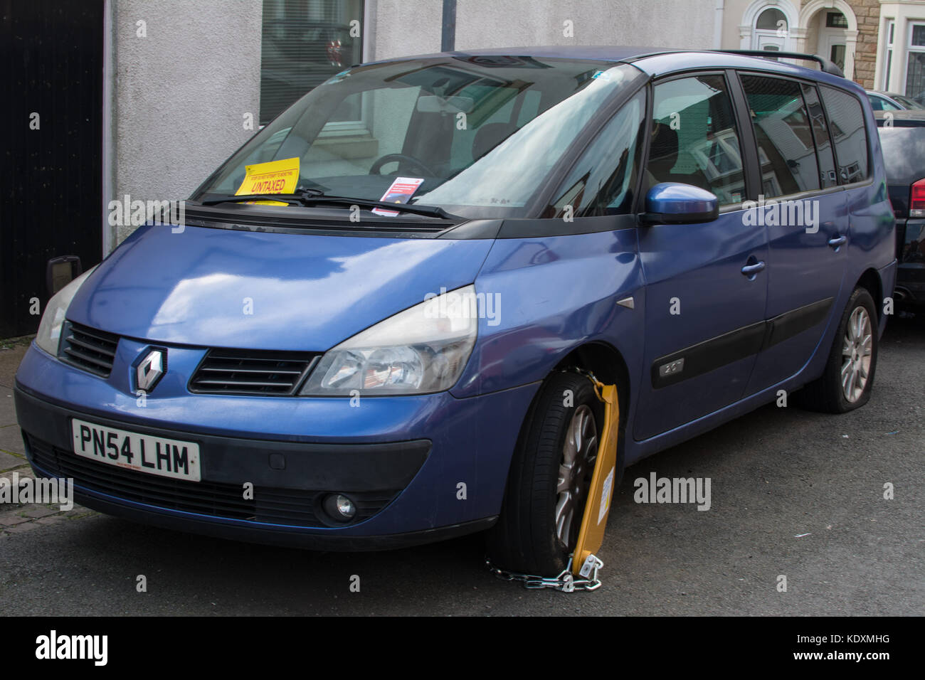 Untaxed car Renault car blue metallic colour  ticket fined fine clamp clamped sign signs badge tinted window windows tax taxed untaxed parked fined Stock Photo