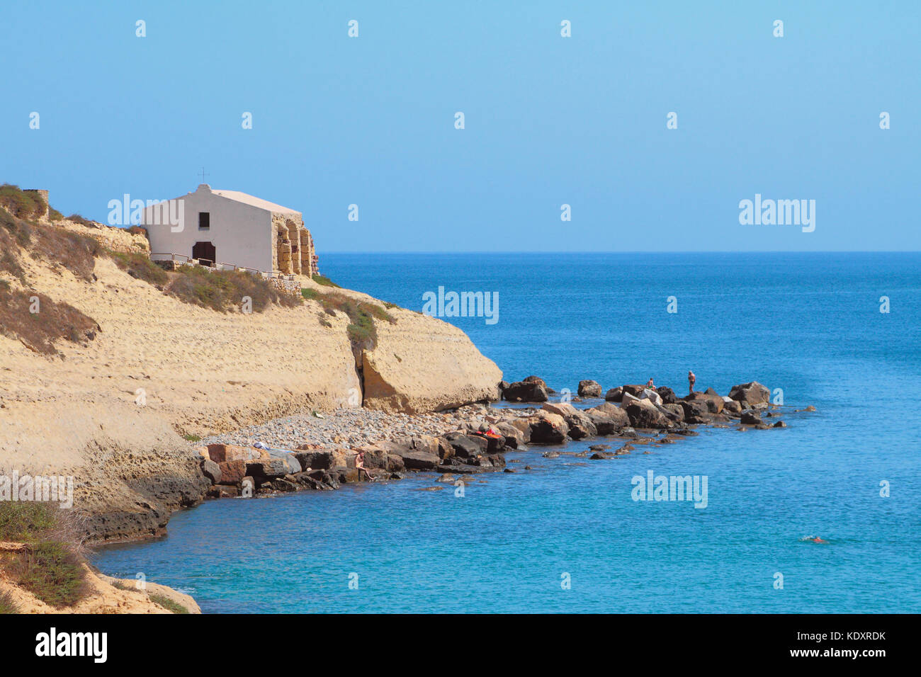 Sea, rocky coast and church. Porto-Torres, Italy Stock Photo