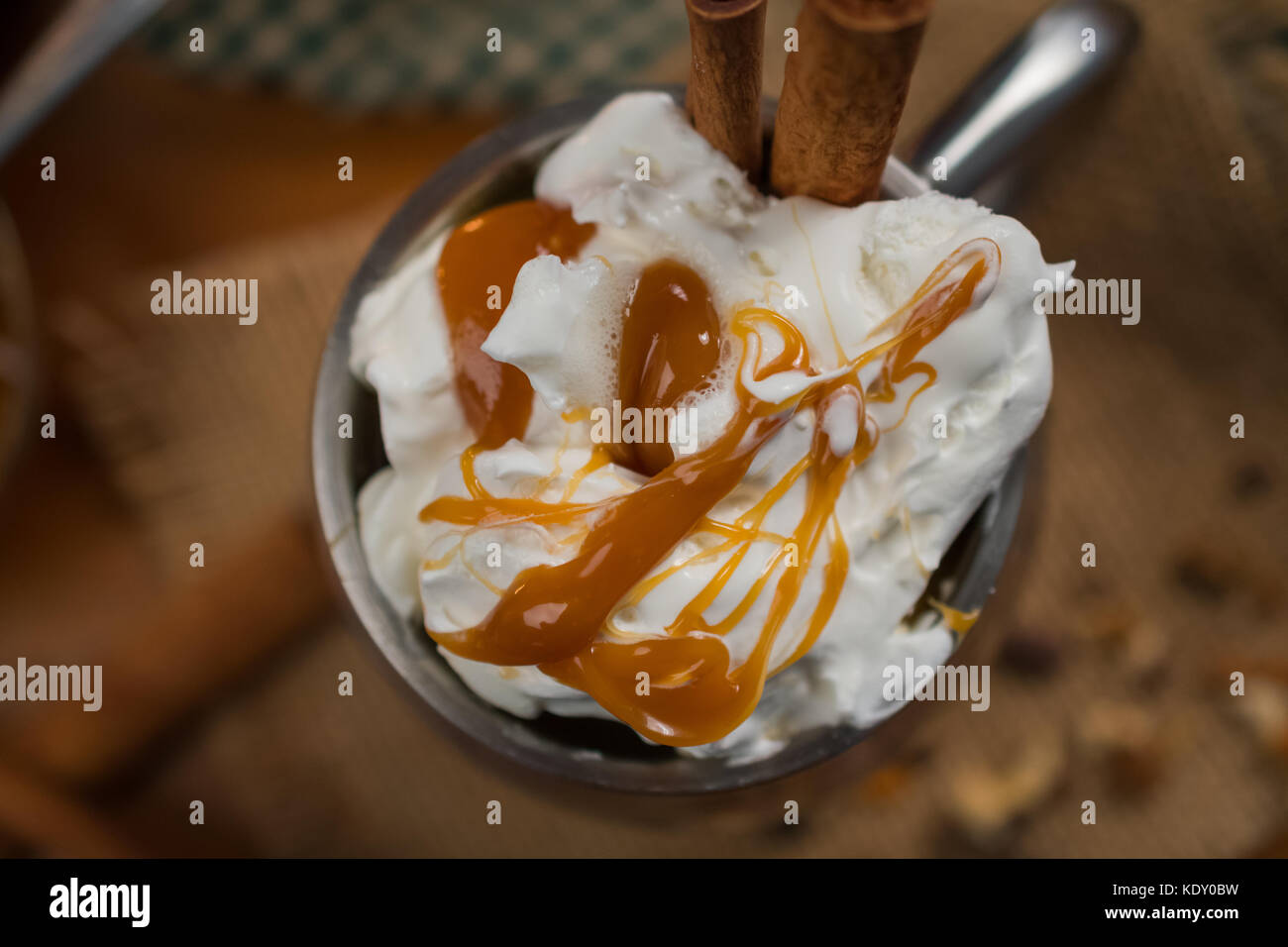 Top view of cup with whipped cream, cinnamon sticks and drizzled caramel Stock Photo