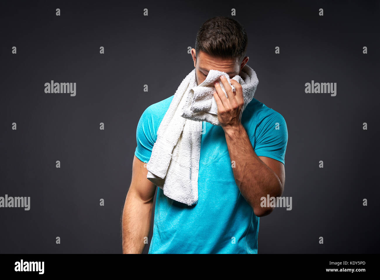 A handsome young sportsman feeling tired and wiping his face with a towel Stock Photo