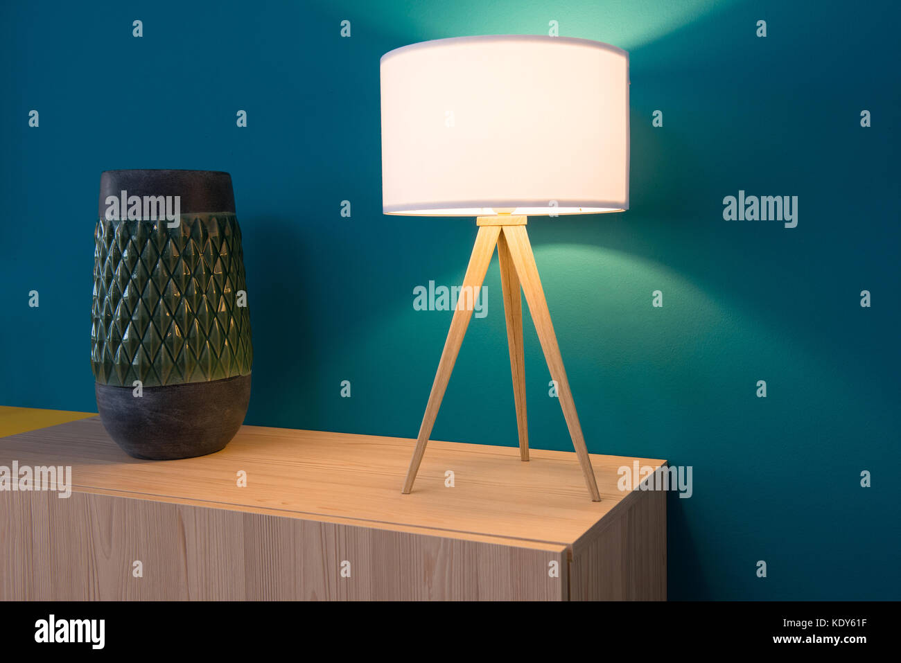 Lamp and vase on cabinet, blue wall in background Stock Photo
