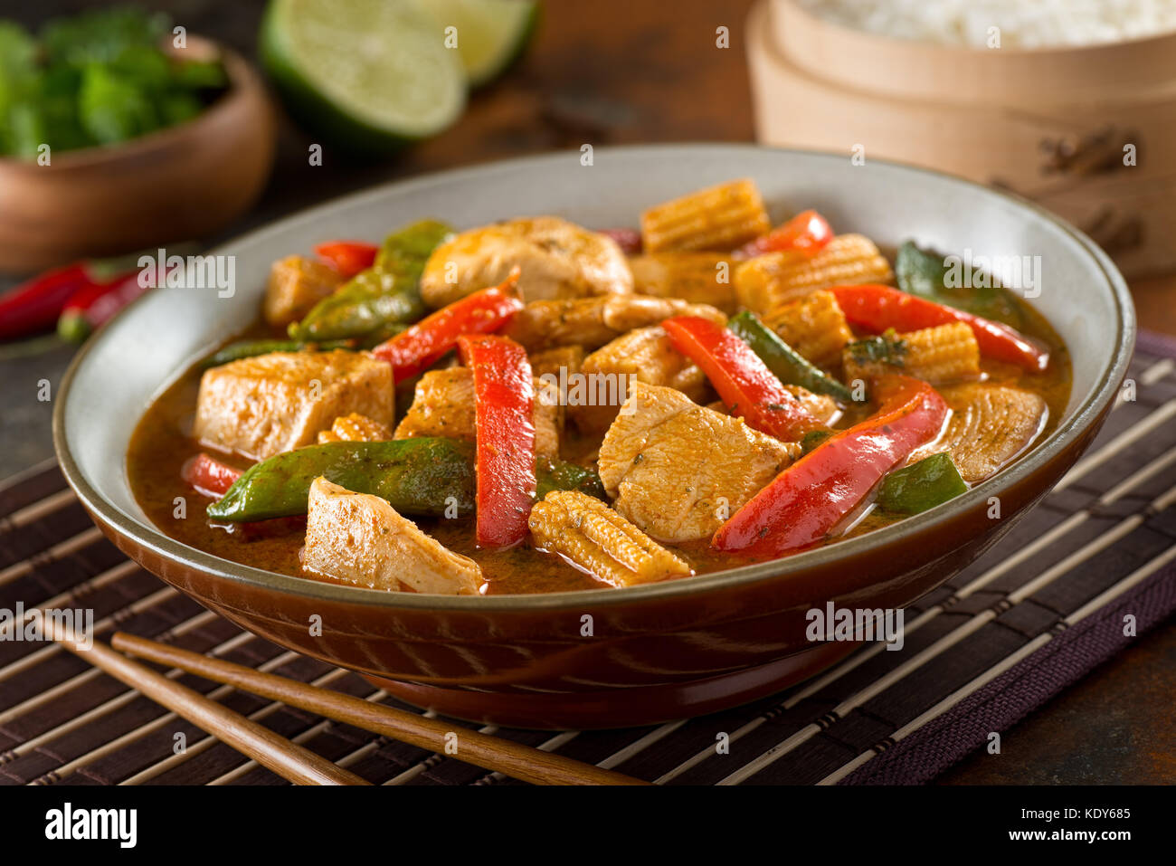 Delicious homemade thai red curry with chicken, red pepper, snow peas, baby corn, coconut milk and cilantro. Stock Photo