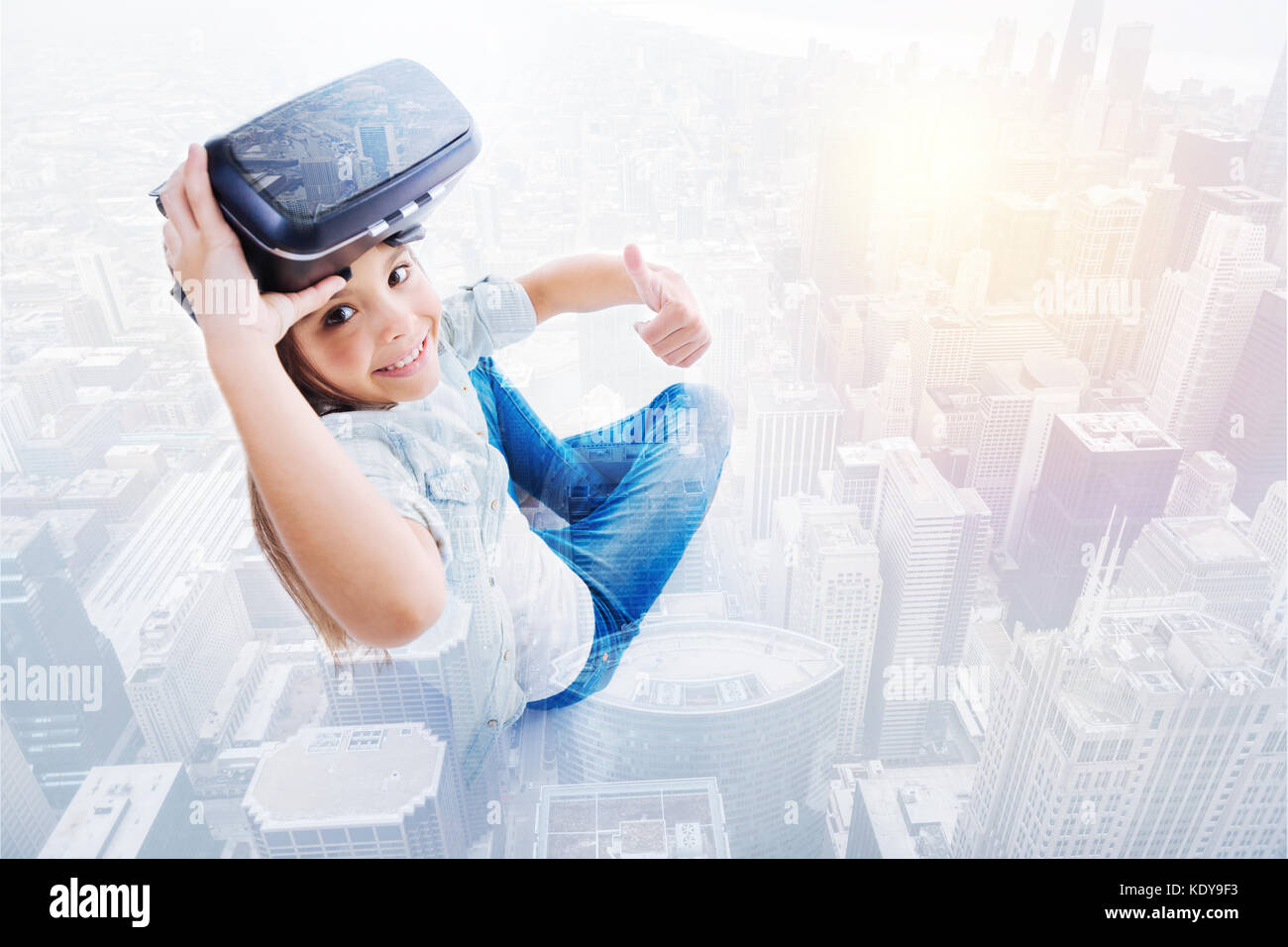 Cute girl showing thumbs up while removing VR headset Stock Photo