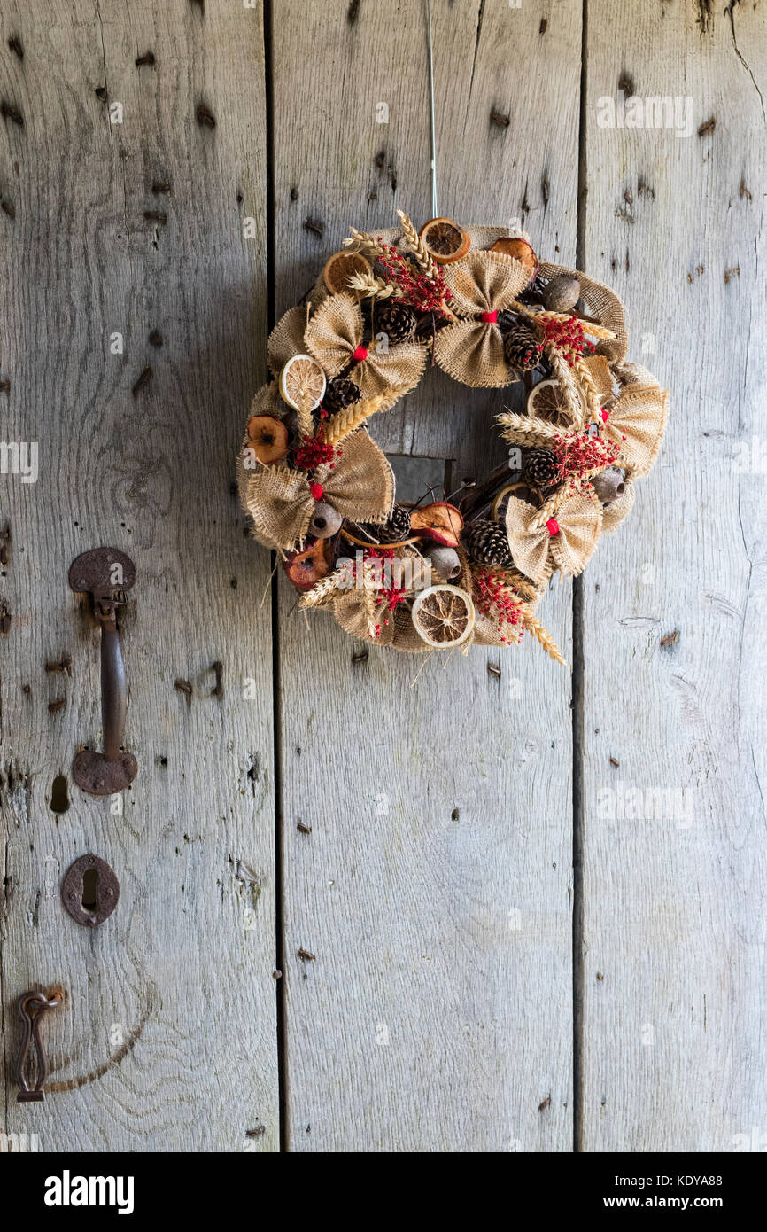 Autumnal rustic harvest festival wreath on an old oak door at Weald and Downland open air museum, autumn countryside show, Singleton, Sussex, England Stock Photo