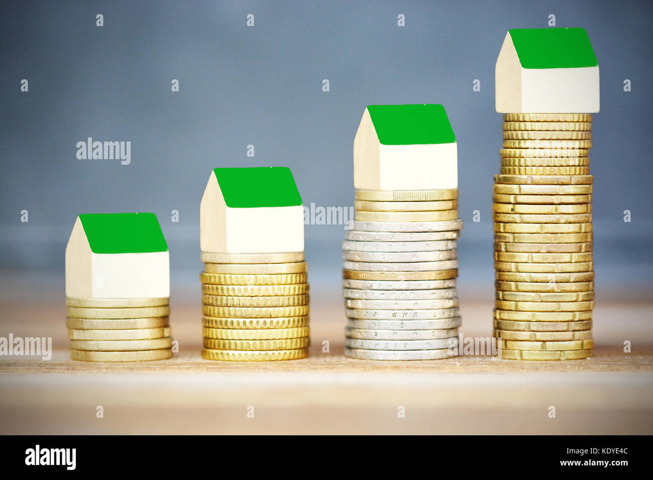 Real estate price evolution concept with miniature wooden houses on ascending piles of money Stock Photo