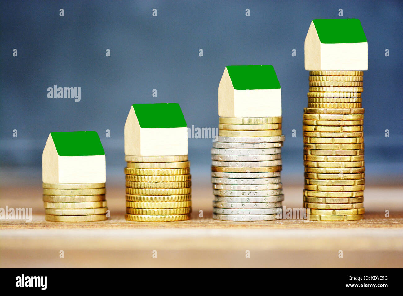 Real estate price evolution concept with miniature wooden houses on ascending piles of money Stock Photo