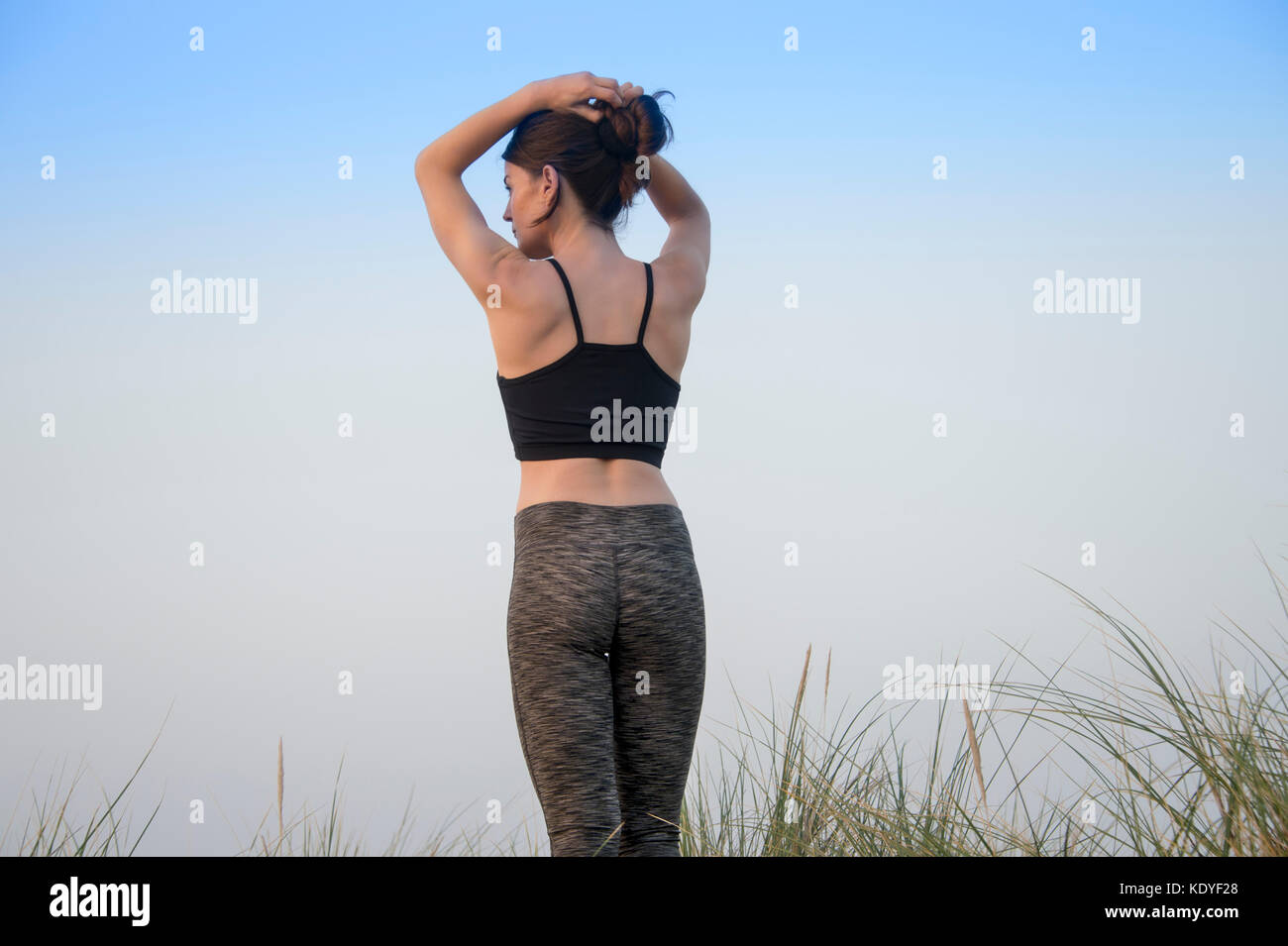 back view of a sporty woman tying her hair up before exercising outside Stock Photo