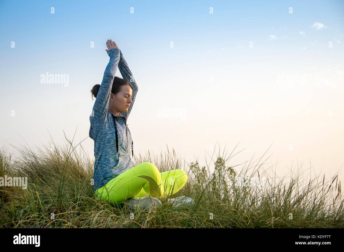 woman meditating in the sand dunes at sunrise/sunset , yoga practice Stock Photo