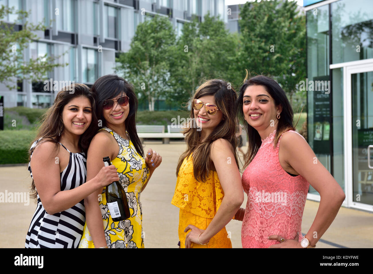 Four young women celebrating outside office buildings during the day Stock Photo