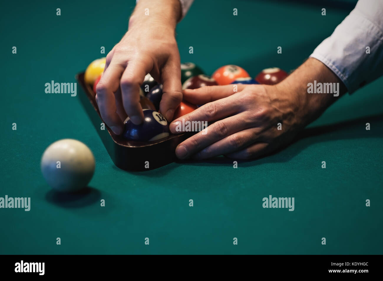 Playing billiard. Billiards balls on green billiards table. Caucasian player put ball inside. View from side. Stock Photo