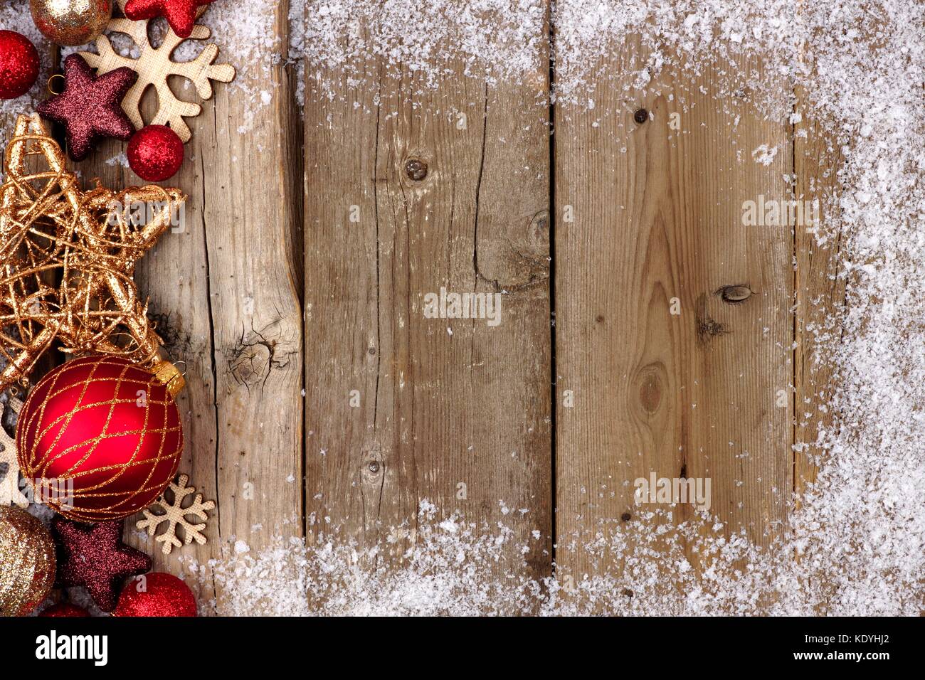 Red and gold Christmas ornament side border with snow frame on a rustic ...