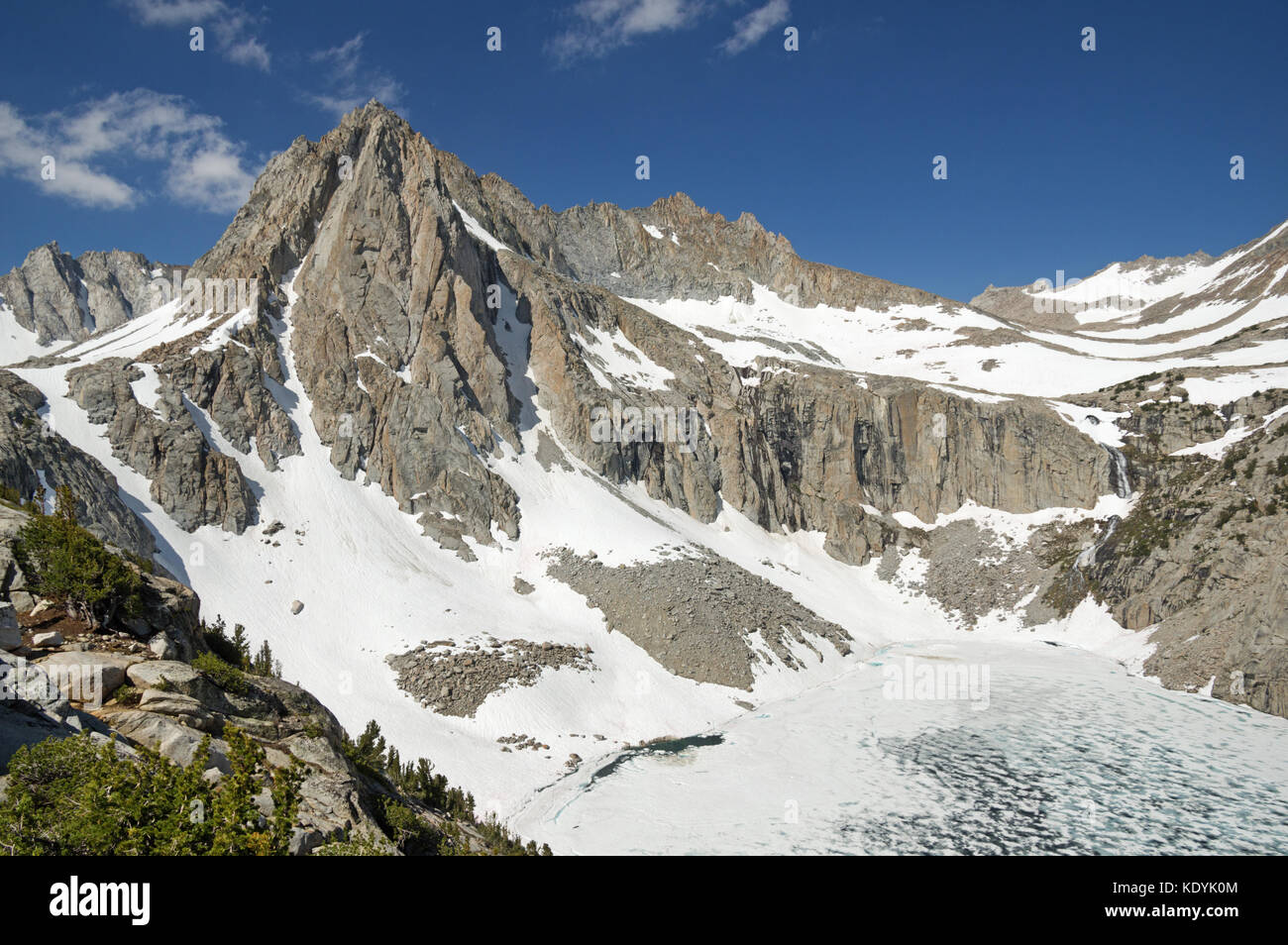 Picture Peak Mountain rises above a still mostly frozen Hungry Packer Lake in the Sierra Nevada Mountains of California Stock Photo