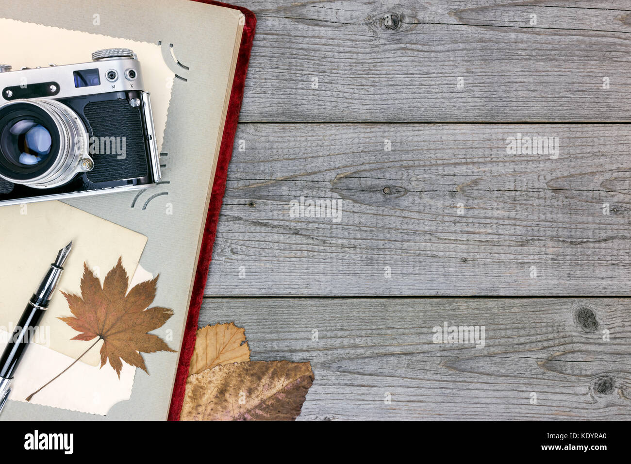 still retro camera, photo album, pen and yellow leaves on grunge wooden background Stock Photo