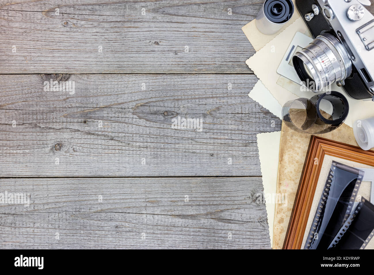 still retro camera, films and old photos on wooden surface background flat view Stock Photo