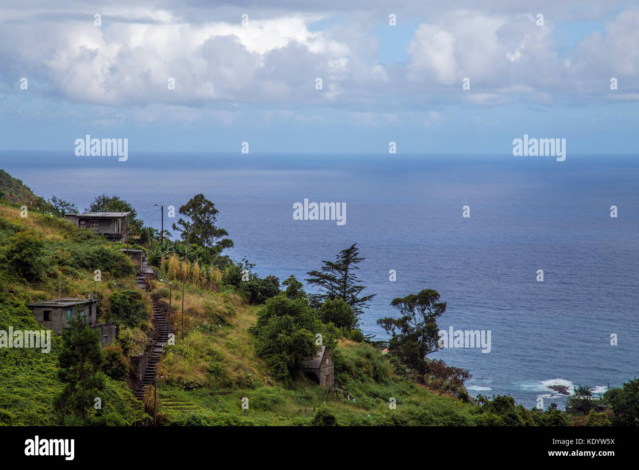 Dramatic view of green mountains with houses and ocean view with cloudy ...