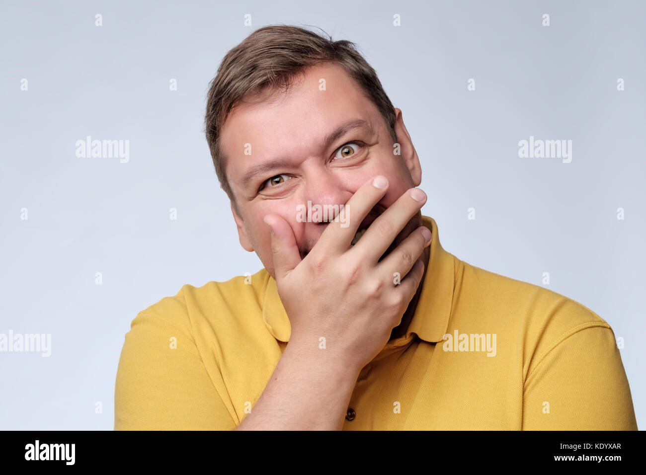 Mature fat man studio portrait. He closes his mouth with delight. Stock Photo