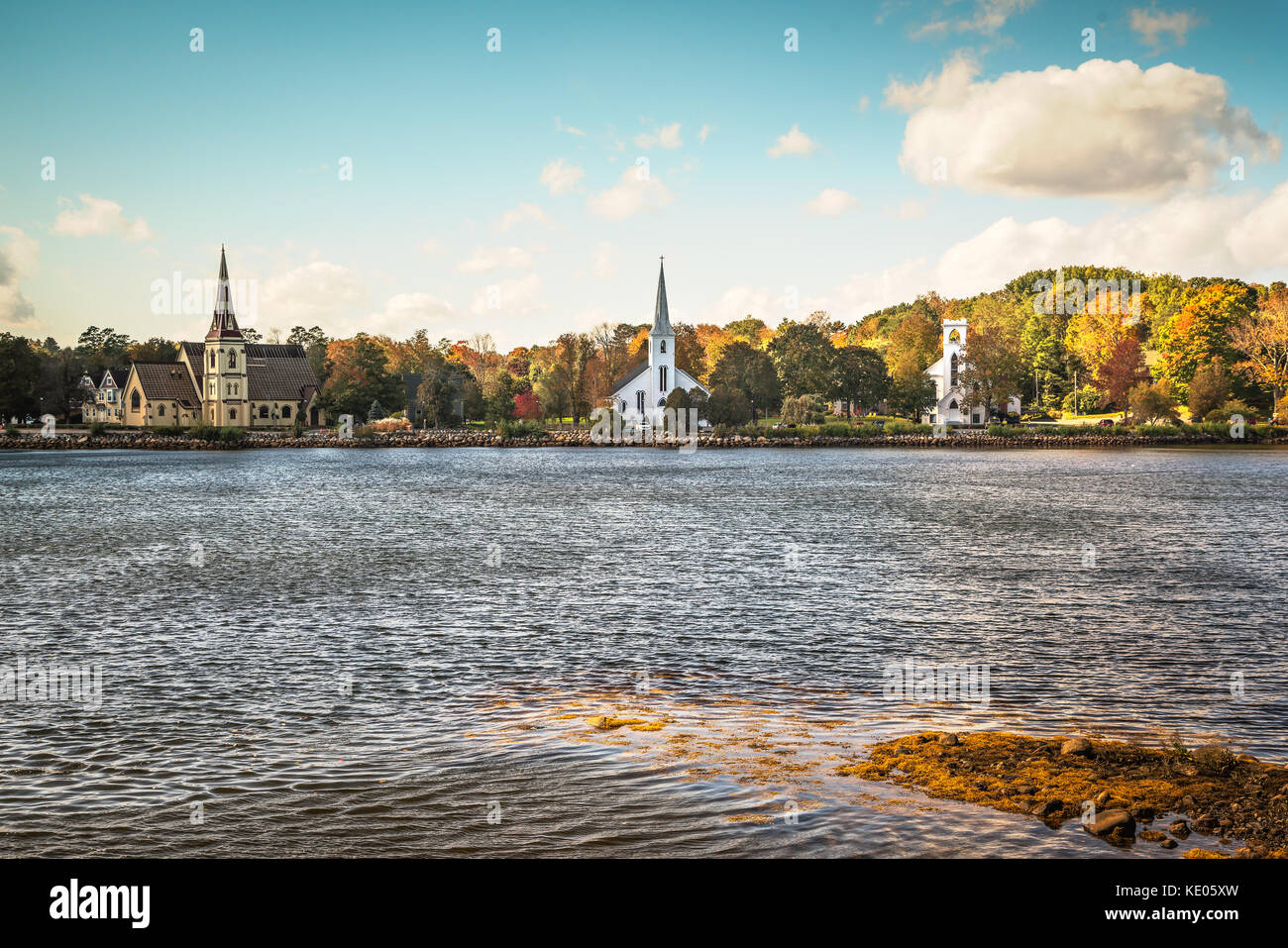 Shoreline view of the village of  Mahone Bay in Nova Scotia, Canada on a perfect Autumn day.  Three churches are visible on the banks of the inlet. Stock Photo