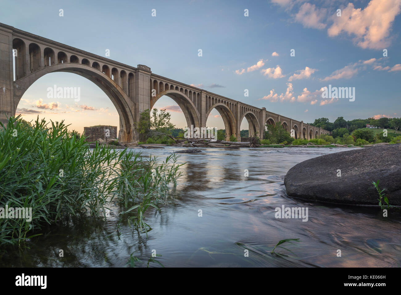 A graceful, arched railroad bridge spans the James River near Richmond, Virginia, USA. Stock Photo