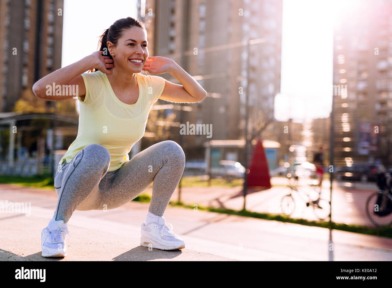 Young woman doing squats in urban area Stock Photo Alamy