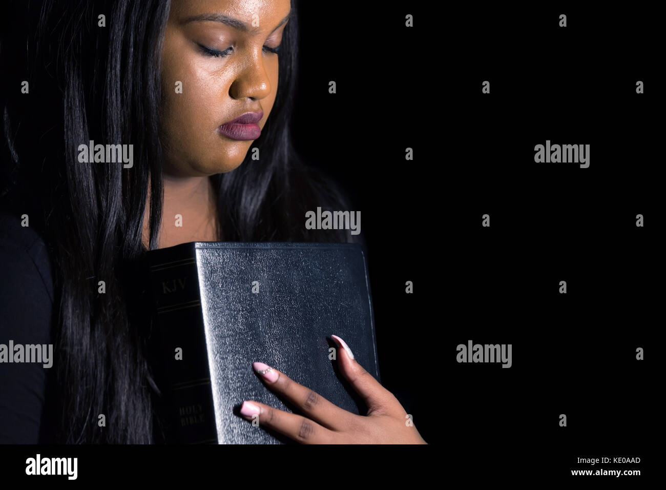 Persecuted Young Girl Holding Her Bible in the Darkness Stock Photo