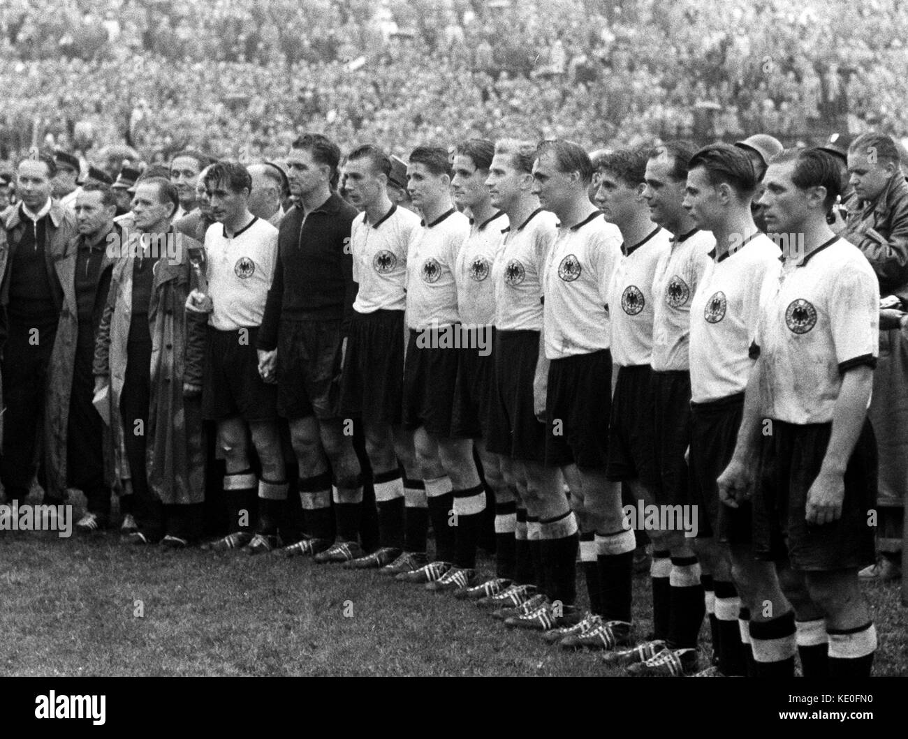 ARCHIVE - The German national team stands before 53000 spectators after their 3-2 victory against Hungary at the World Cup at the Wankdorf Stadium in Bern, Switzerland, 4 July 1954. From Left to Right: head coach Sepp Herberger, captain Fritz Walter with the Jules-Rimet-Cup, goalkeeper Toni Turek, Horst Eckel, Helmut Rahn, Ottmar Walter, Werner Liebrich, Jupp Posipal, Hans Schäfer, Werner Kohlmeyer, Karl Mai and Max Morlock. To the left of Herberger stand Adolf Dassler (L) and masseur Erich Deuser (2-L). Hans Schaefer will turn 90 years old on the 19th of October 2017. Photo: Richard Koll/dpa Stock Photo