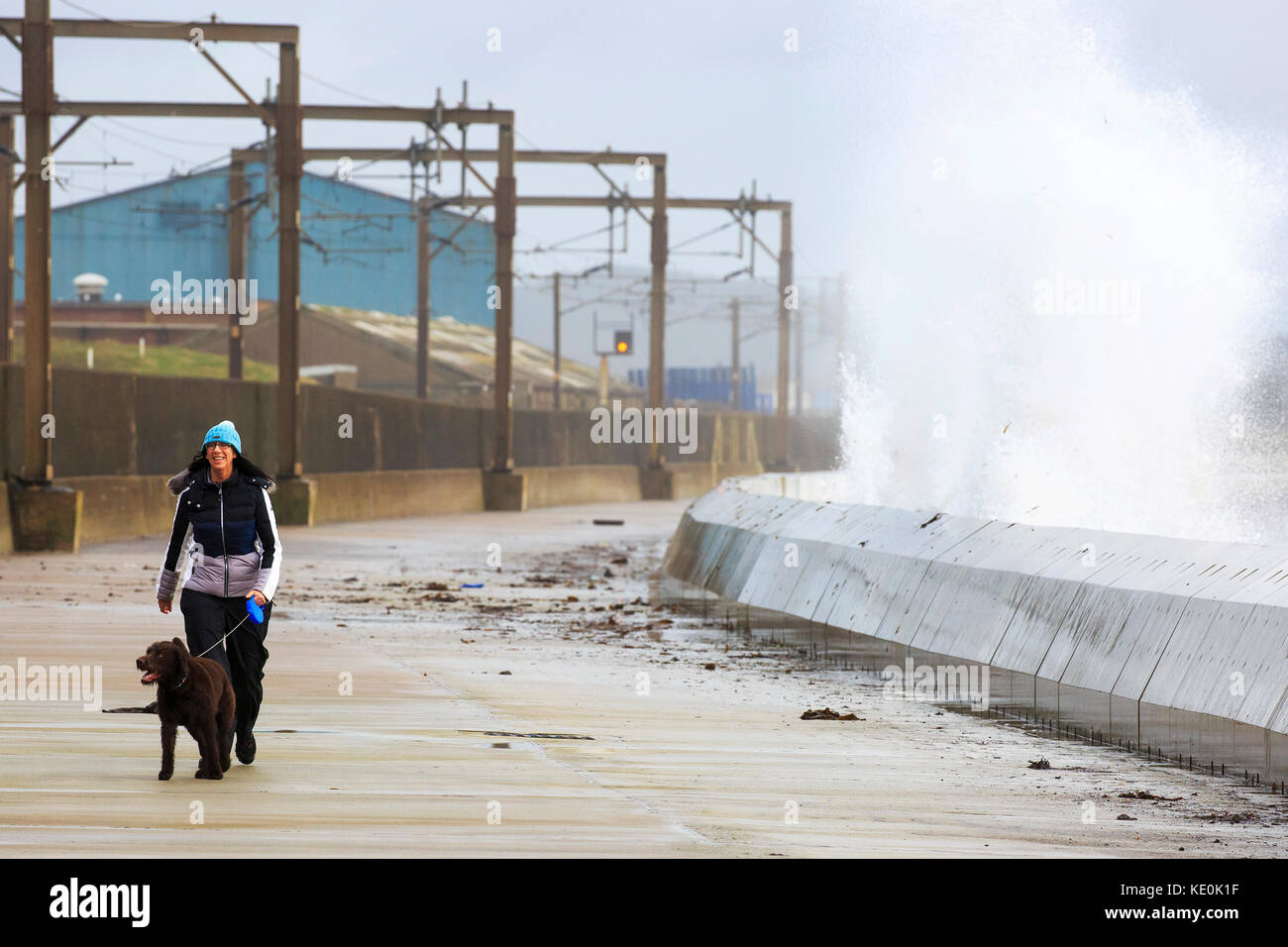 Life gets back to normal on the day after Hurricane Ophelia struck the west coast of Scotland with winds gusting up to 80 mph and as winds continue to cause high waves and stormy conditions, locals in Saltcoats, Ayrshire get on with their regular dog walking. Stock Photo