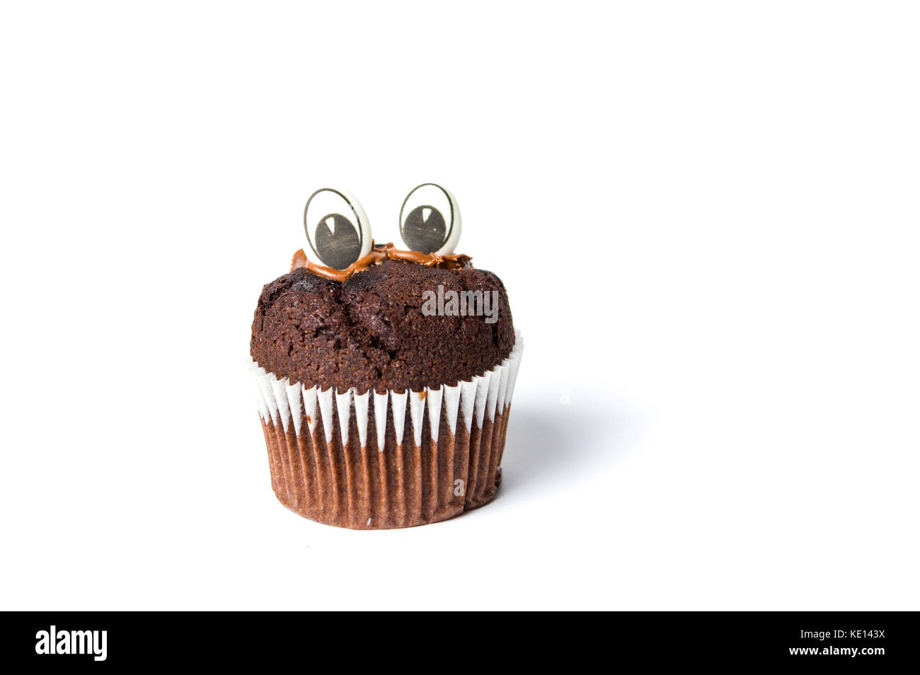 Chocolate muffin with edible eyes in paper holder on white Stock Photo