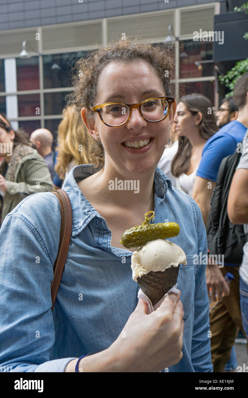 A woman with an ice cream cone garnished with a sour pickel at the