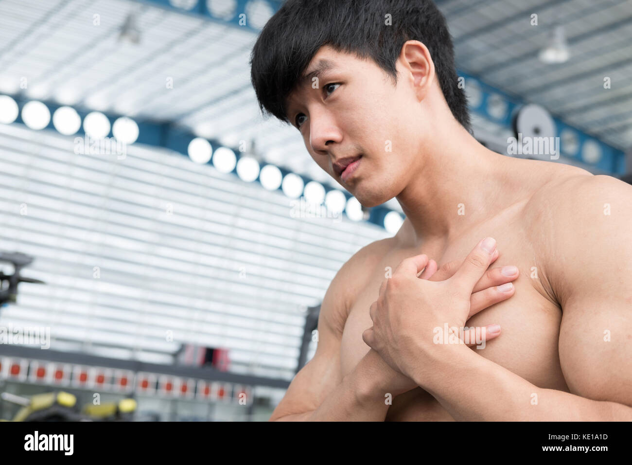 muscular male having chest pain in gym. young man injure while workout