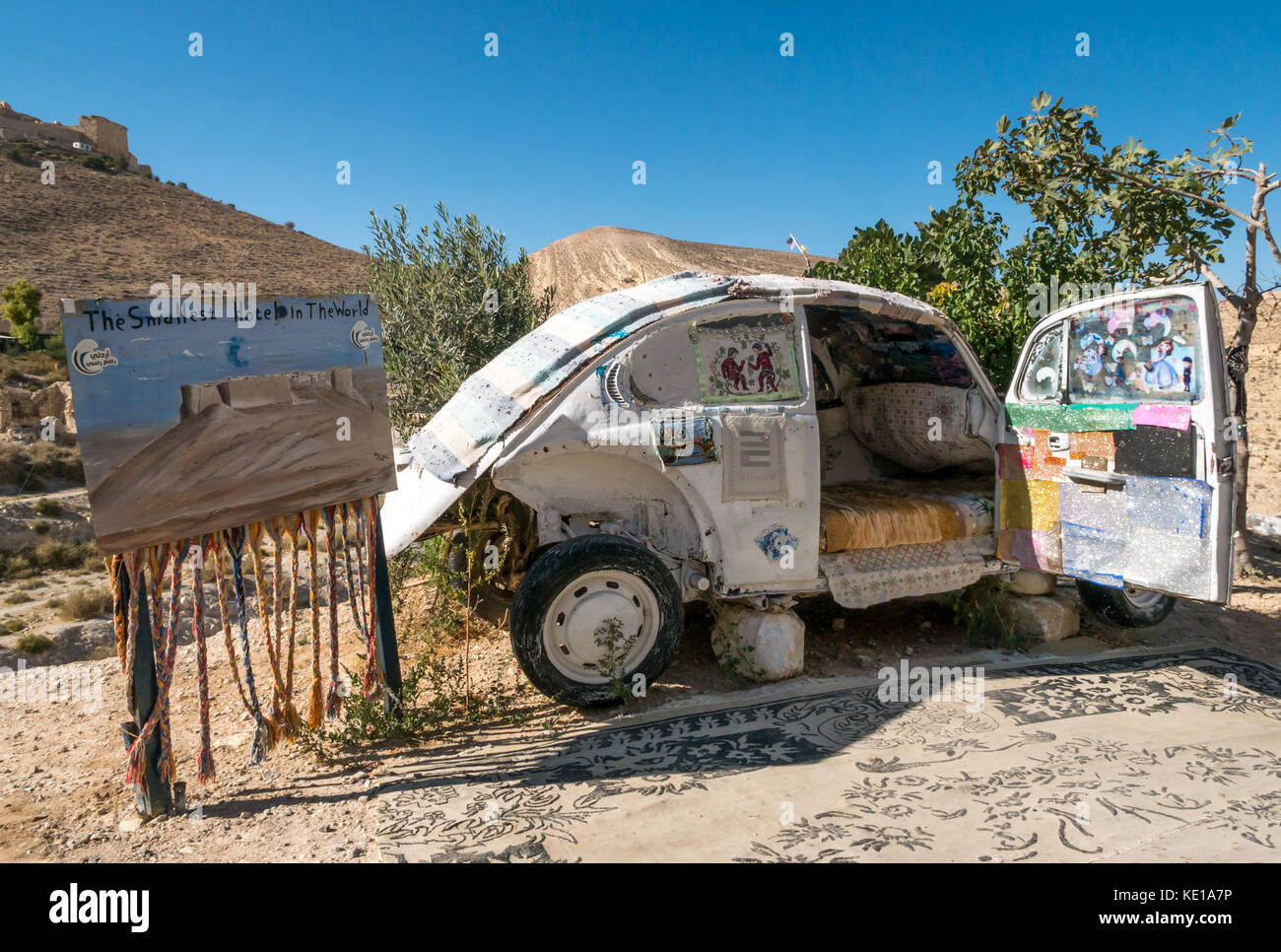 Humorous advert for the smallest hotel in the world, old vintage small car converted to a bed with Shoubak Castle, Jordan, Middle East Stock Photo