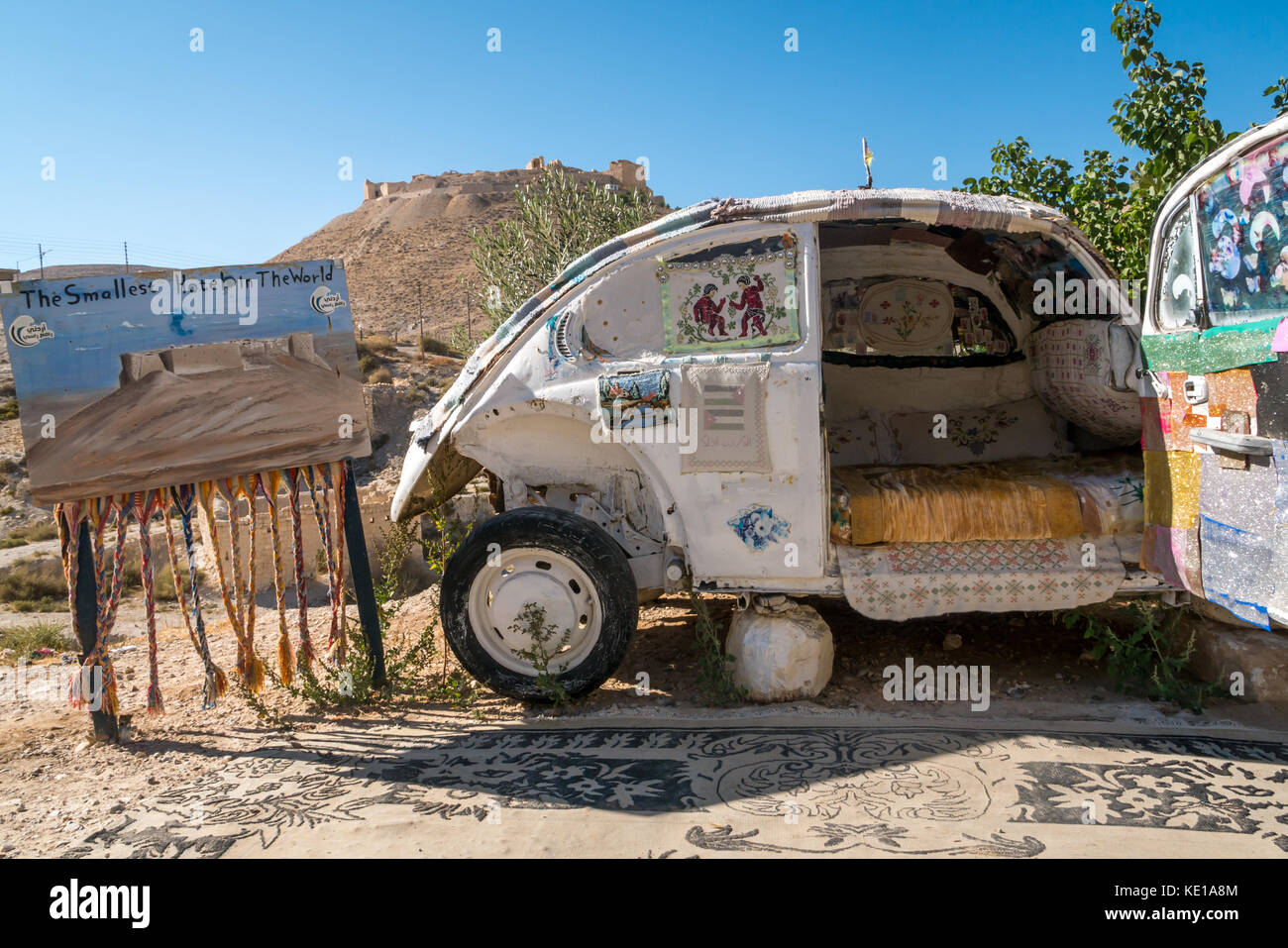 Humorous advert for the smallest hotel in the world, old vintage small car converted to a bed with Shoubak Castle, Jordan, Middle East Stock Photo