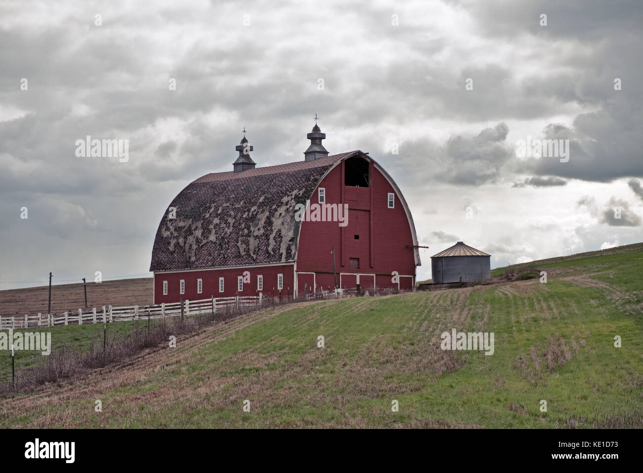 A traditional red barn on a farm stands on one of the rolling hills in
