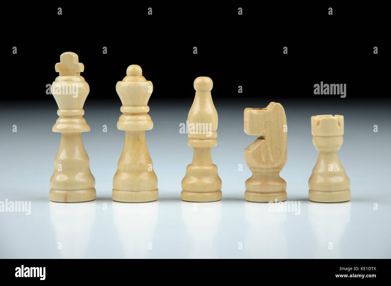 Close-up view of a row of white chess pieces on a black-white blurred background with reflection Stock Photo
