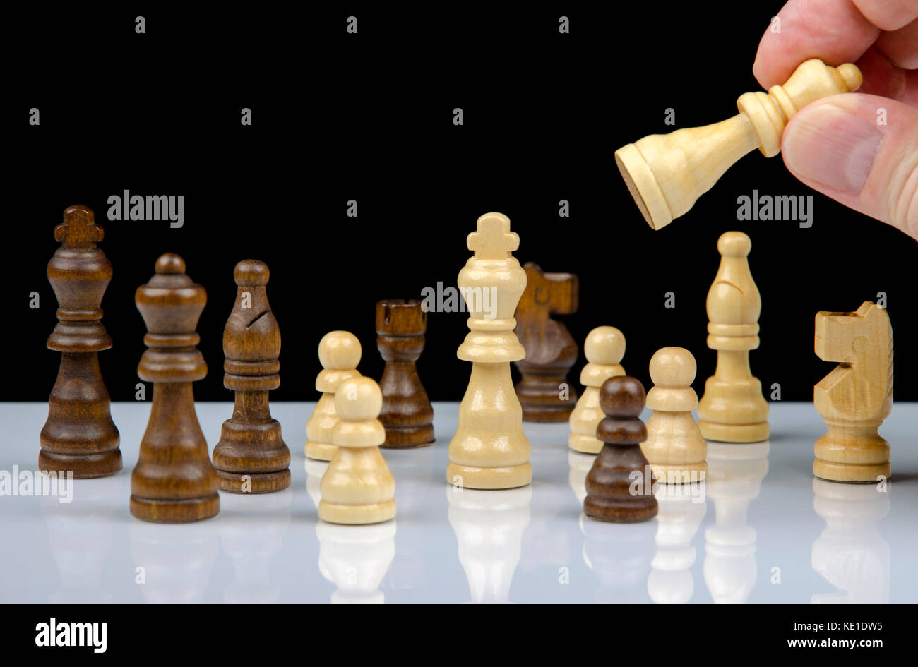 Close-up view of chess pieces with reflection on white background with hand holding queen isolated on black background Stock Photo