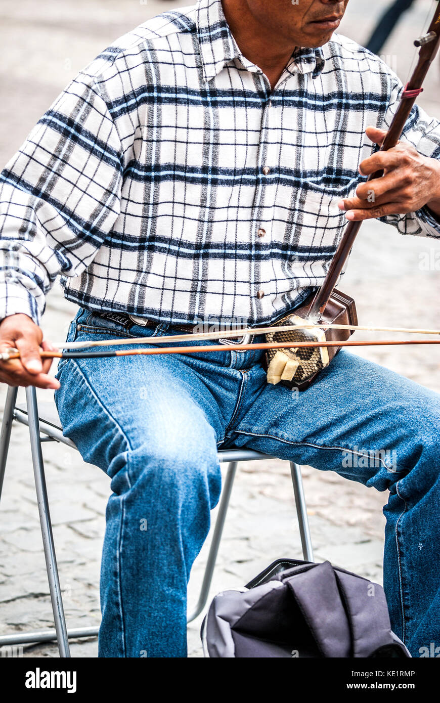 man plays an erhu, two-stringed bowed fiddle. The Erhu is an ancient Asian instrument, brought to China 140 B.C. Stock Photo