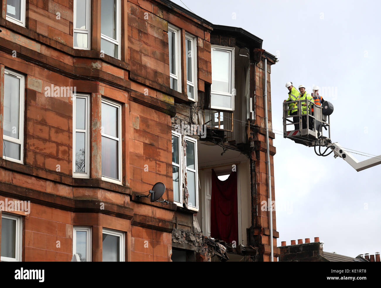 Workmen survey the damage to a block of flats in Crosshill, in the south side of Glasgow, after part of the front was brought down in high winds as Storm Ophelia sweeps across Scotland. Stock Photo