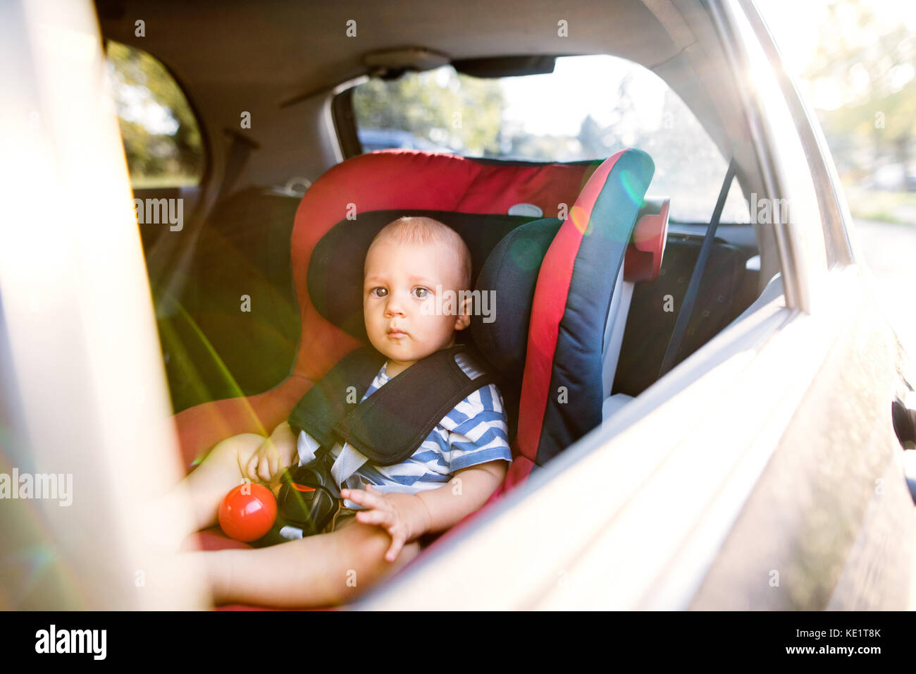 Cute little baby boy sitting in the car seat in the car, looking out. Stock Photo