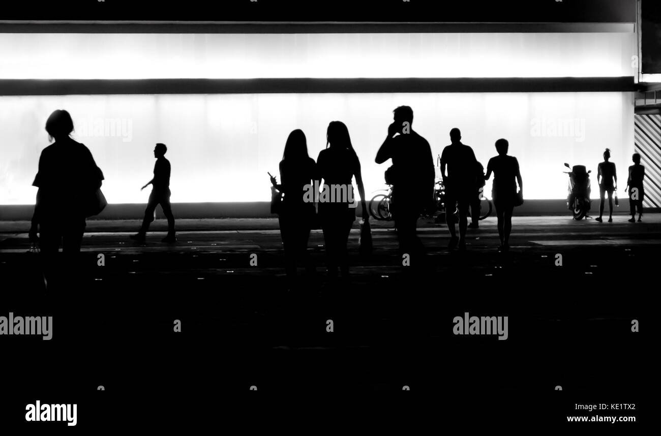 Blurry silhouettes of  people getting out of the building in the night Stock Photo