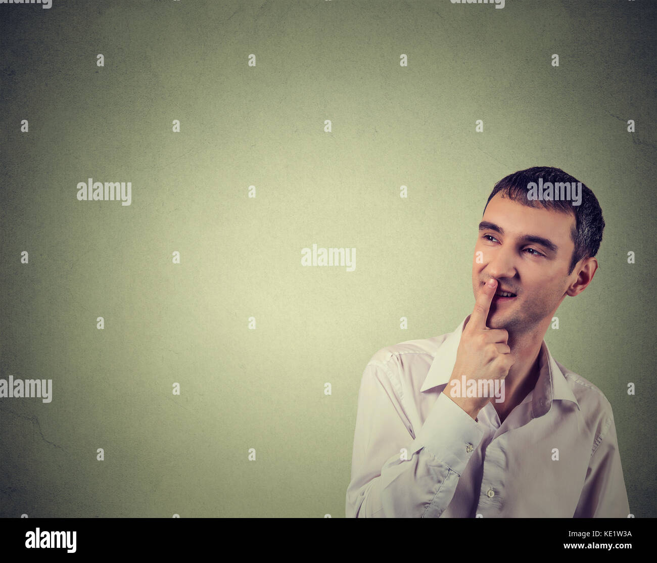 Portrait happy man thinking looking up isolated on gray wall background with copy space. Human face expressions, emotions, feelings, body language, pe Stock Photo
