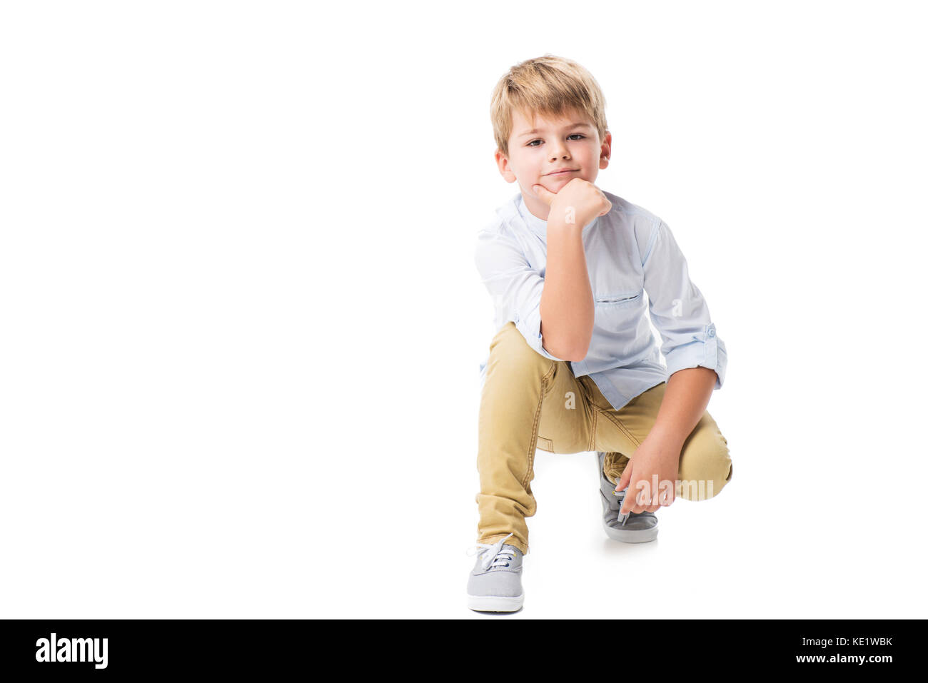 adorable little boy kneeling and looking at camera isolated on white Stock Photo