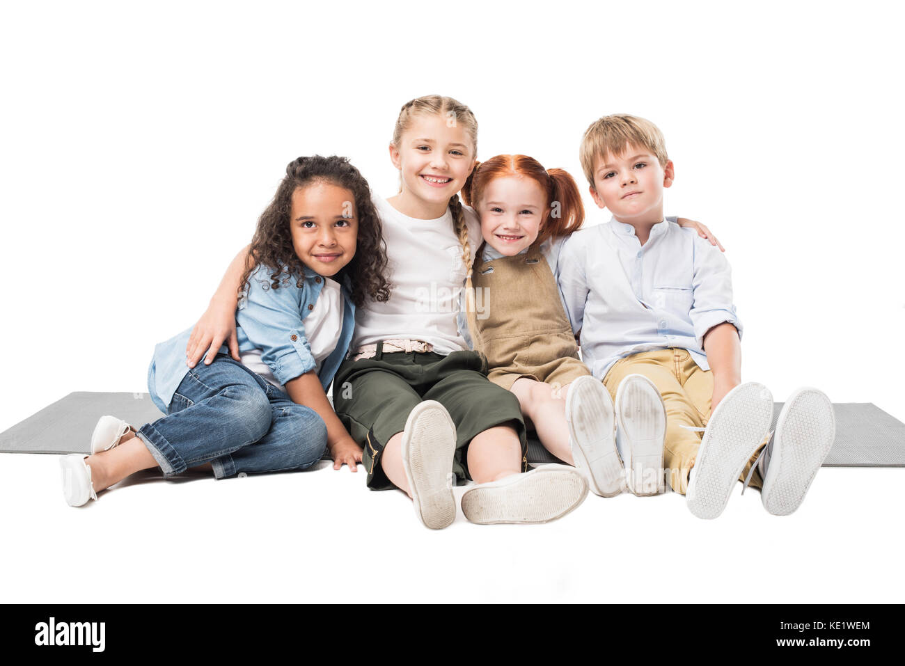 happy multiethnic children sitting together isolated on white Stock Photo