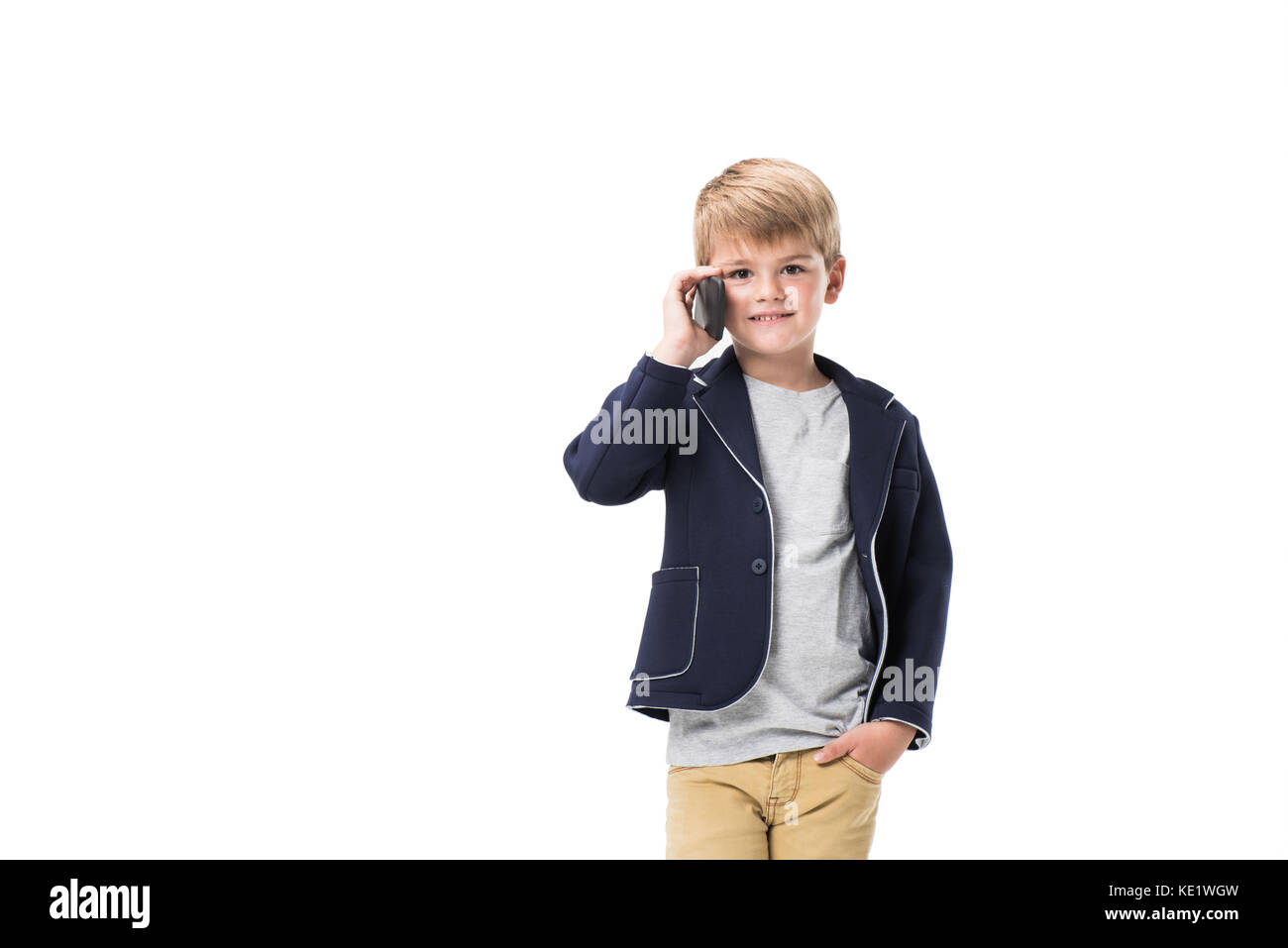 cute smiling boy talking on smartphone and looking at camera isolated on white Stock Photo